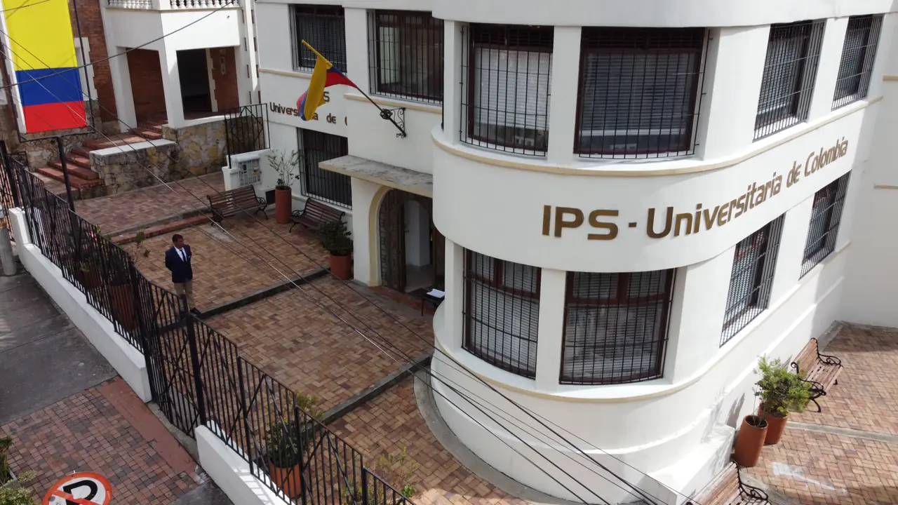 Video aéreo de la IPS Universitaria de Colombia: parte del letrero de la fachada y se aleja hasta mostrar la calle y las casas vecinas